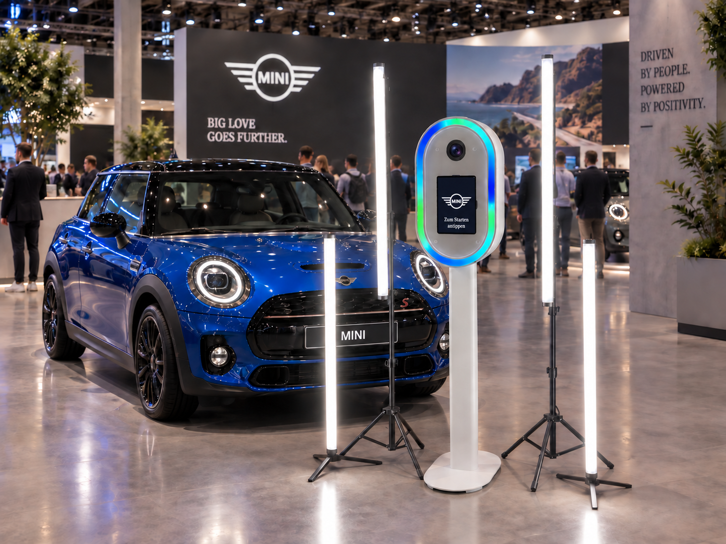 KI-Fotobox mit Automotive-Branding, Kamera, Touchscreen und Licht neben einem blauen Fahrzeug auf einem Messestand · Konzeptvisualisierung