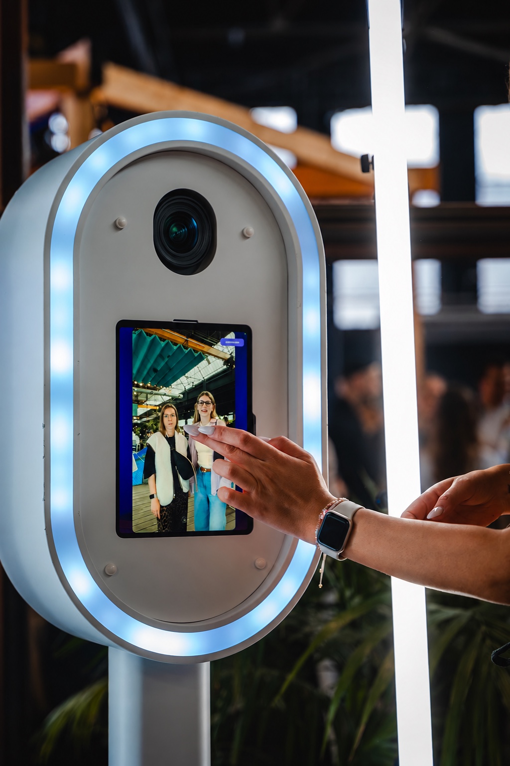 Gast bedient den Touchscreen der weißen Fotobox mit integrierter Kameralinse